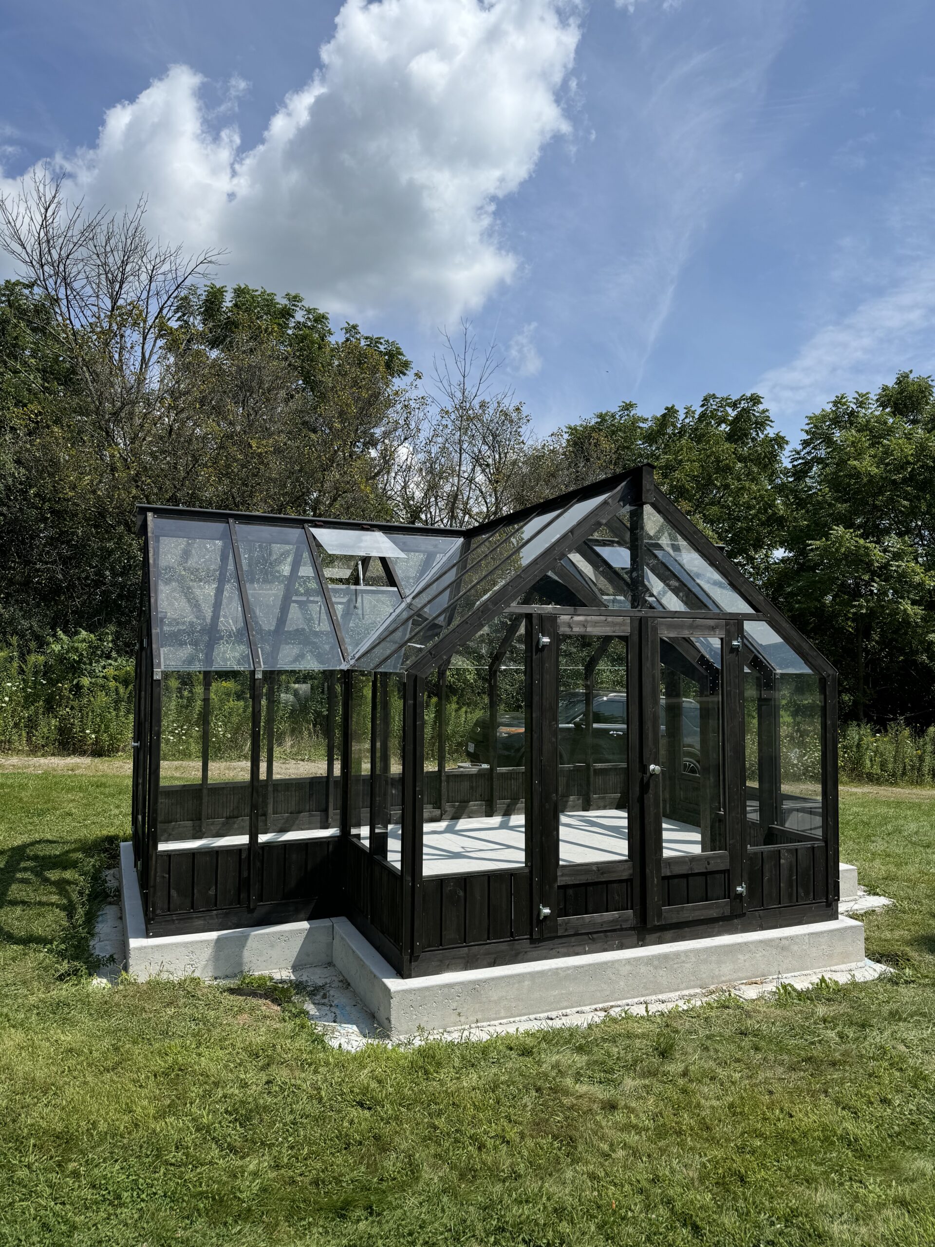 A beauitful greenhouse on a sunny day with blue skies and green grass